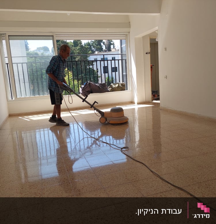 אדם מנקה רצפה עם מכונת פוליש בחדר ריק